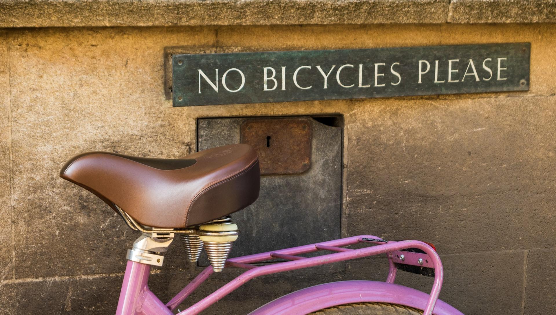 pink bicycle parked beside brown concrete wall